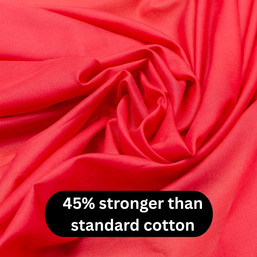 Close-up of bright red fabric with soft folds and a bold black badge reading ‘45% stronger than standard cotton. batiste cotton fabric