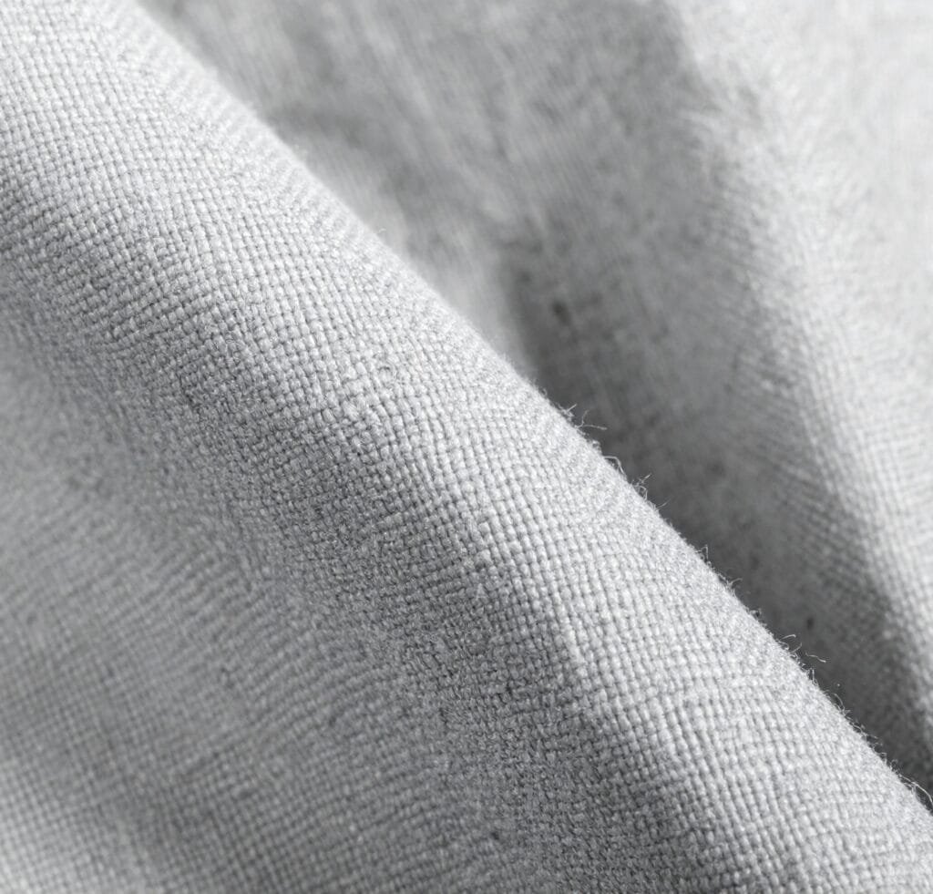 Close-up of light gray canvas linen fabric with visible weave texture and tiny fibers.
