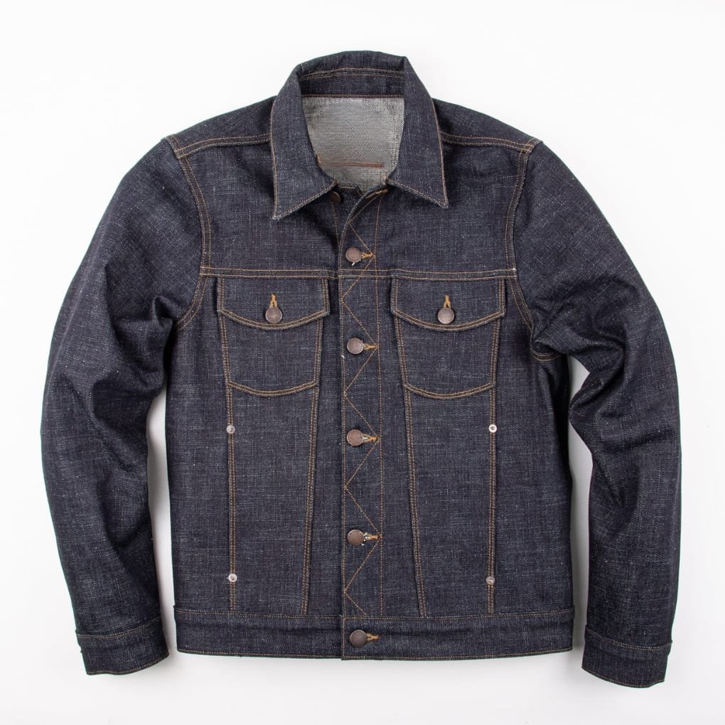 A dark indigo denim jacket with brown contrast stitching, button-front, and two chest pockets, laid flat against a white background.