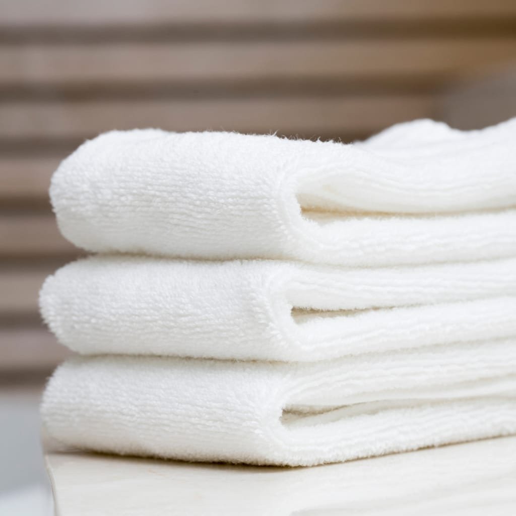 A stack of clean, white towels folded neatly, ready for everyday use.