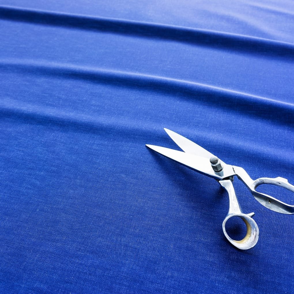 sewing shears resting on a deep blue denim fabric being cut.