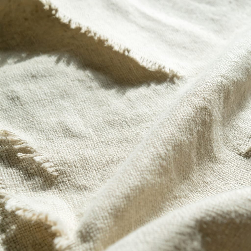 Close-up of a textured, natural-beige fabric with visible weave and soft folds.