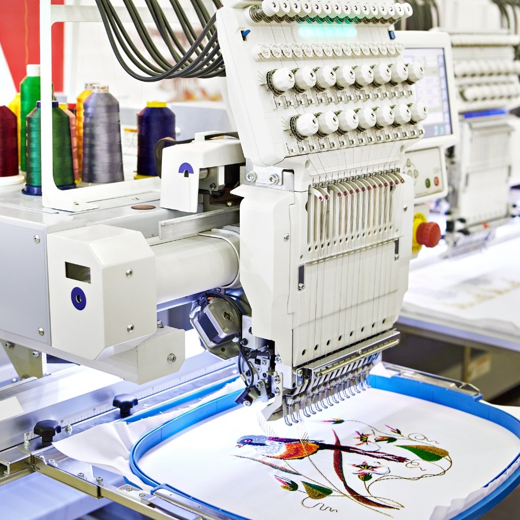 Industrial embroidery machine stitching a colorful design onto velvet wool fabric in a factory setting.