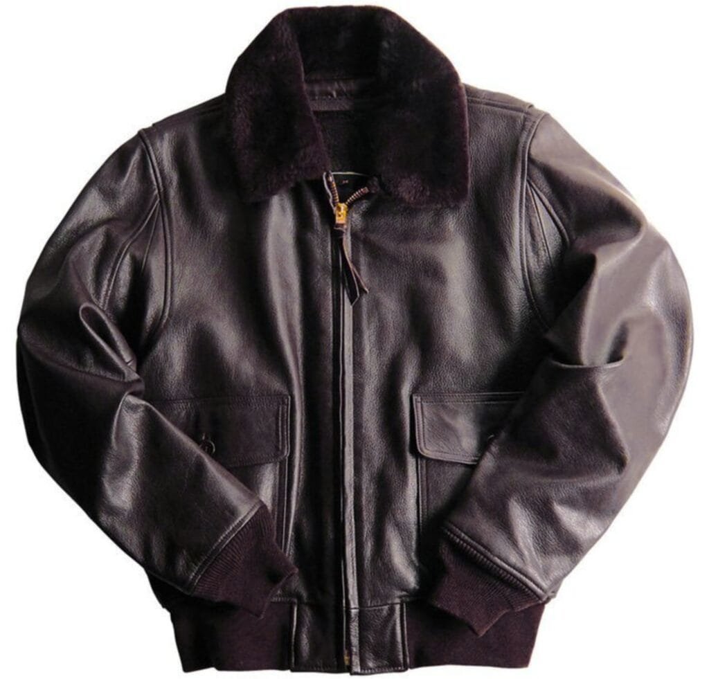 A classic G-1 bomber jacket in deep brown leather with a plush shearling collar, worn by a person standing against a retro-tinged background. The jacket features brass zippers, knit cuffs, and aviation patches on the chest and sleeve, giving it a timeless pop-culture vibe.