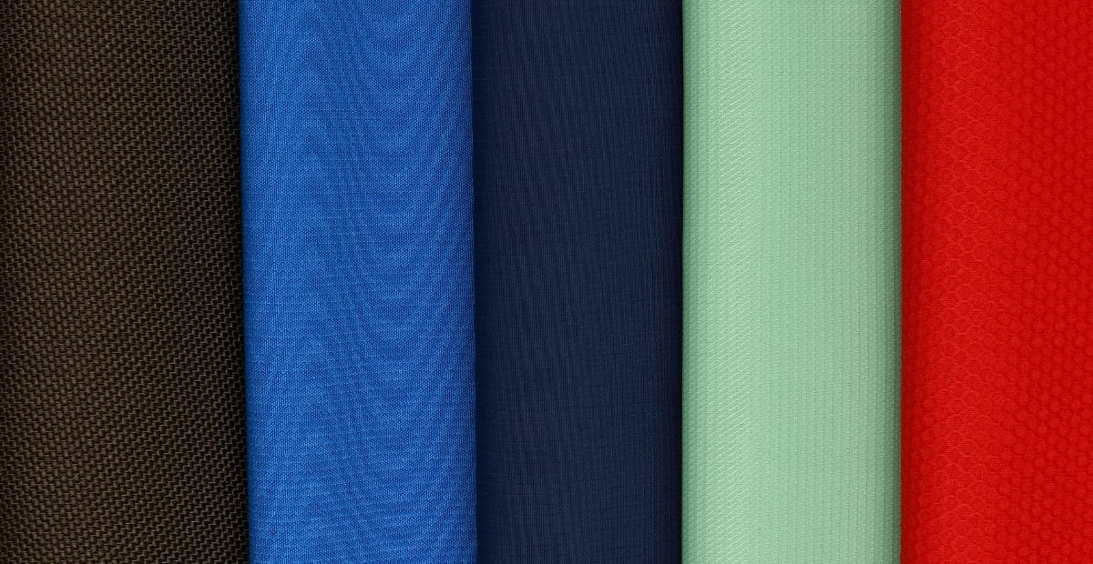High-Tenacity Polyester: Strength, Durability & Key Benefits A row of vertically aligned fabric swatches in different colors, including brown, royal blue, navy, light teal, mint green, and bright red, textured with a woven surface.