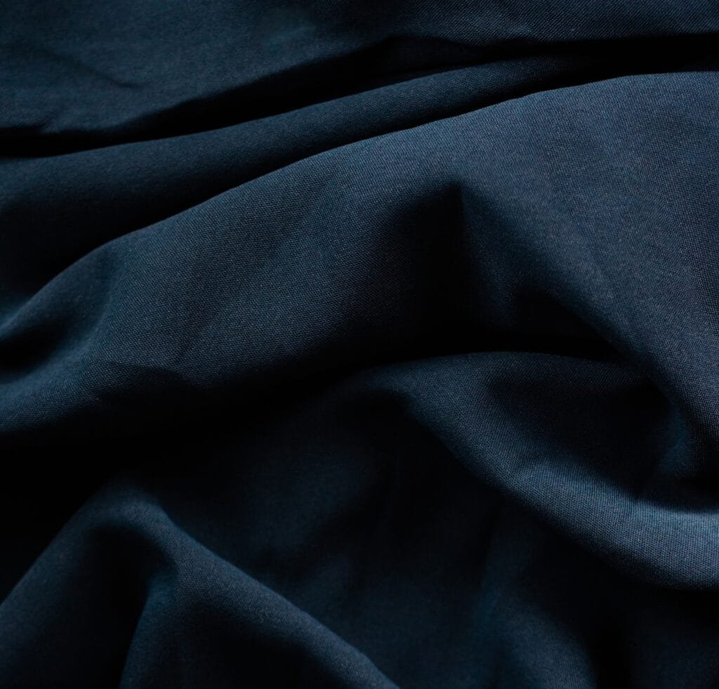  Close-up view of dark navy blue linen fabric with soft folds and shadows.