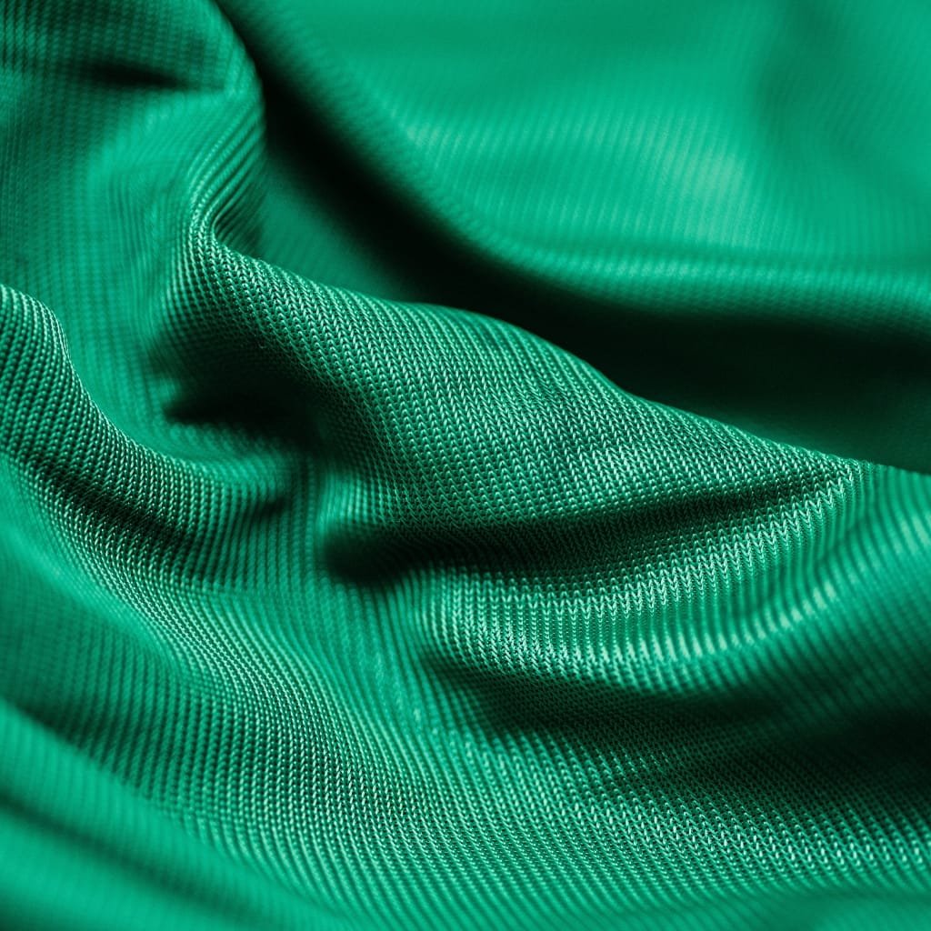 Close-up of vibrant green moisture-wicking polyester fabric with visible micro-weave texture and soft folds.