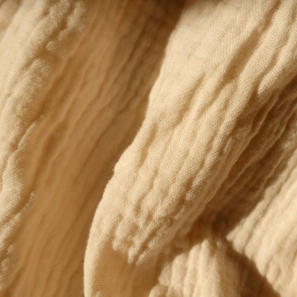 Close-up view of a soft, cream-colored textile with textured, wavy patterns and folds.