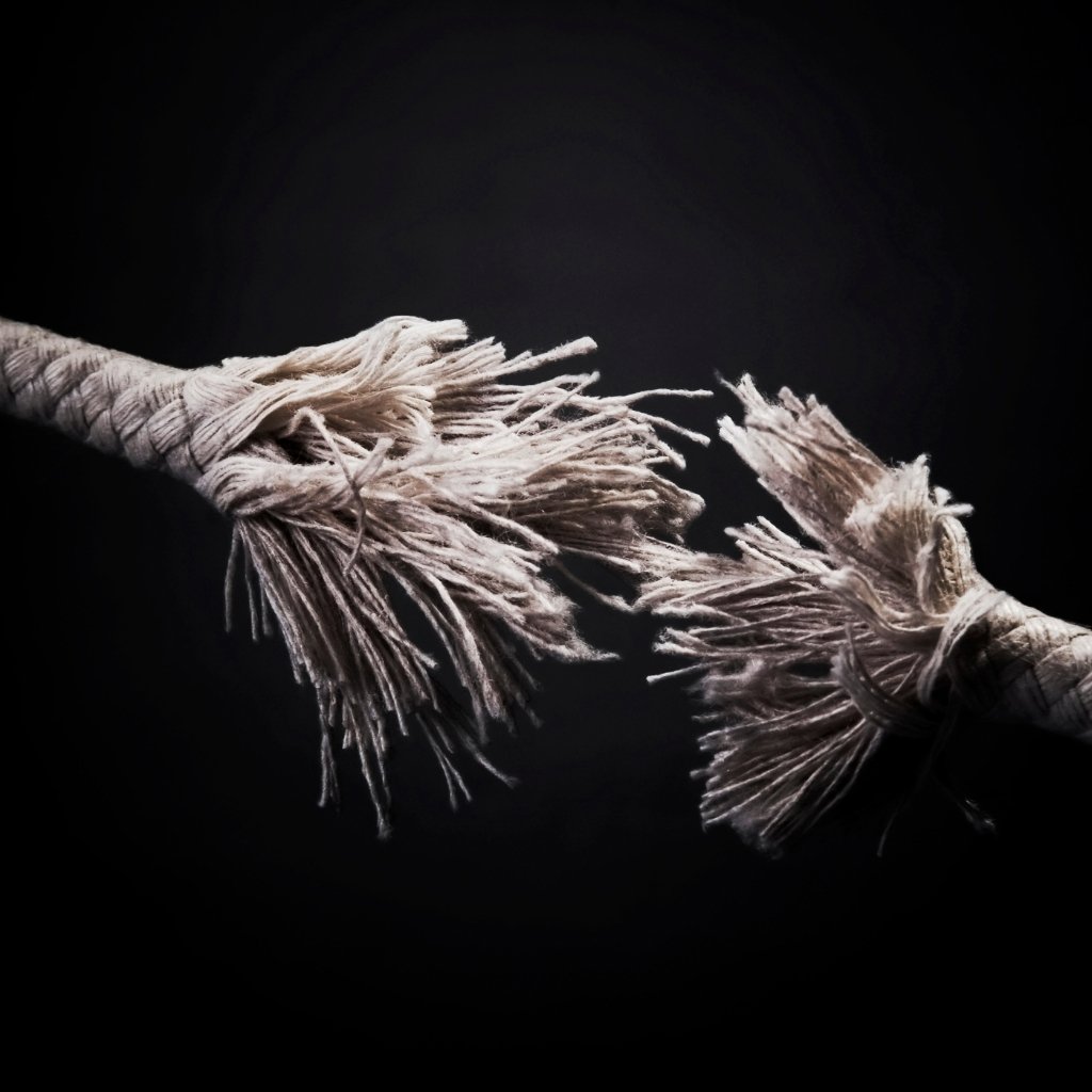 Frayed rope ends breaking apart against a dark background.