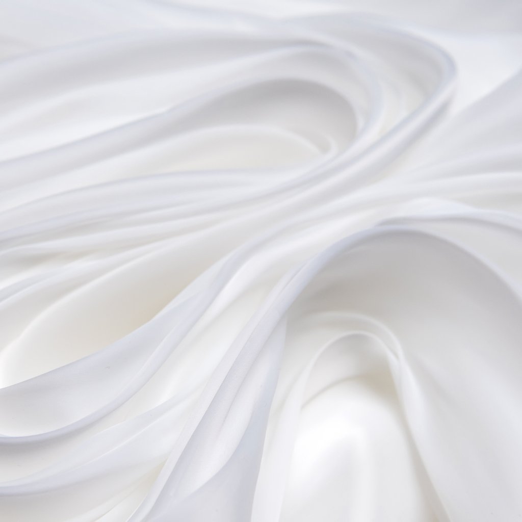 Close-up of flowing, silky satin organza fabric in white, with soft folds and gentle sheen.