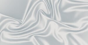 A close-up of smooth, glistening satin organza fabric with soft folds and gentle sheen, showcasing luxurious drape and subtle shadows.