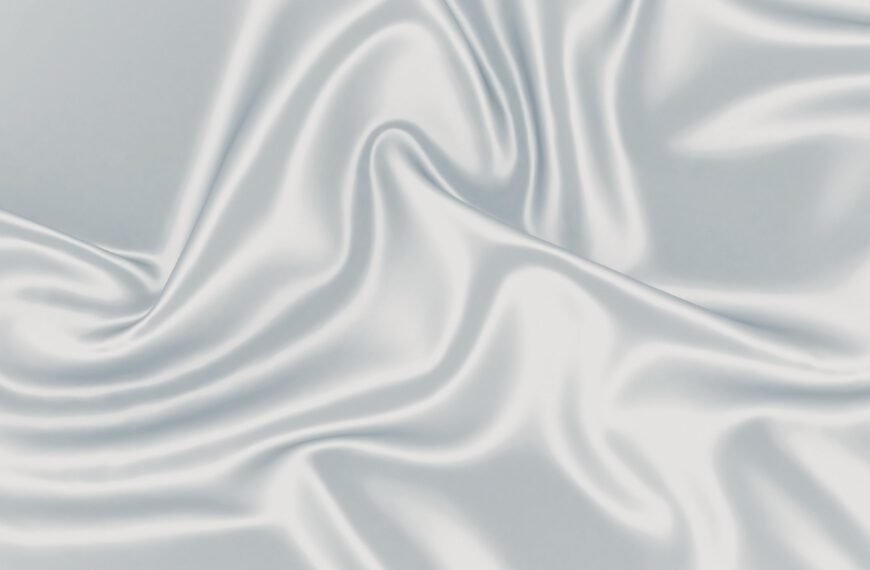 A close-up of smooth, glistening satin organza fabric with soft folds and gentle sheen, showcasing luxurious drape and subtle shadows.