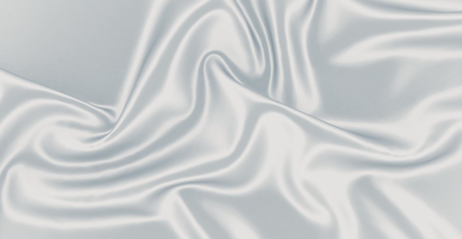 A close-up of smooth, glistening satin organza fabric with soft folds and gentle sheen, showcasing luxurious drape and subtle shadows.