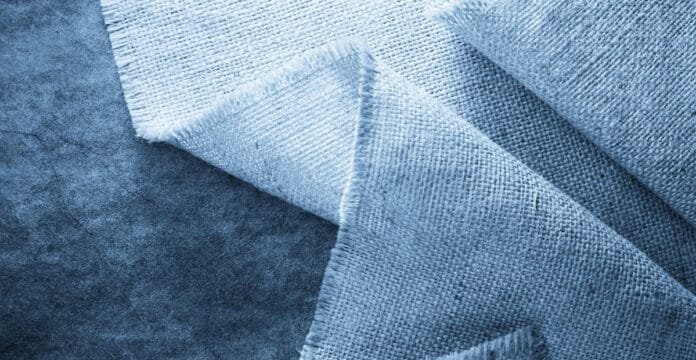 A close-up image of layered blue linen fabric with visible weave texture.