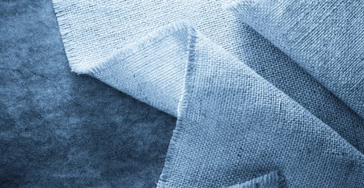 A close-up image of layered blue linen fabric with visible weave texture.