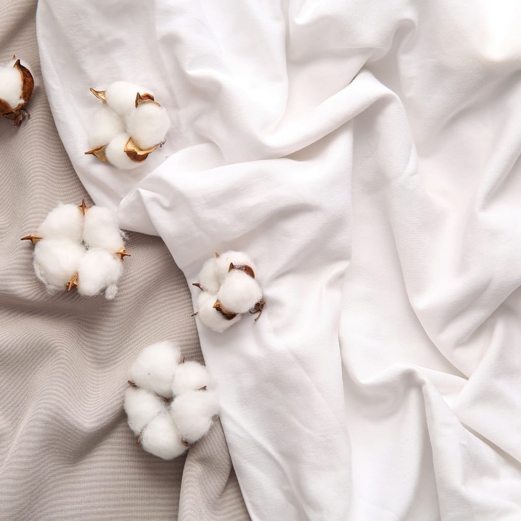 A close-up image of fluffy cotton bolls and soft white Egyptian cotton sheets, artfully arranged to evoke a sense of luxury and comfort for a restful night’s sleep.