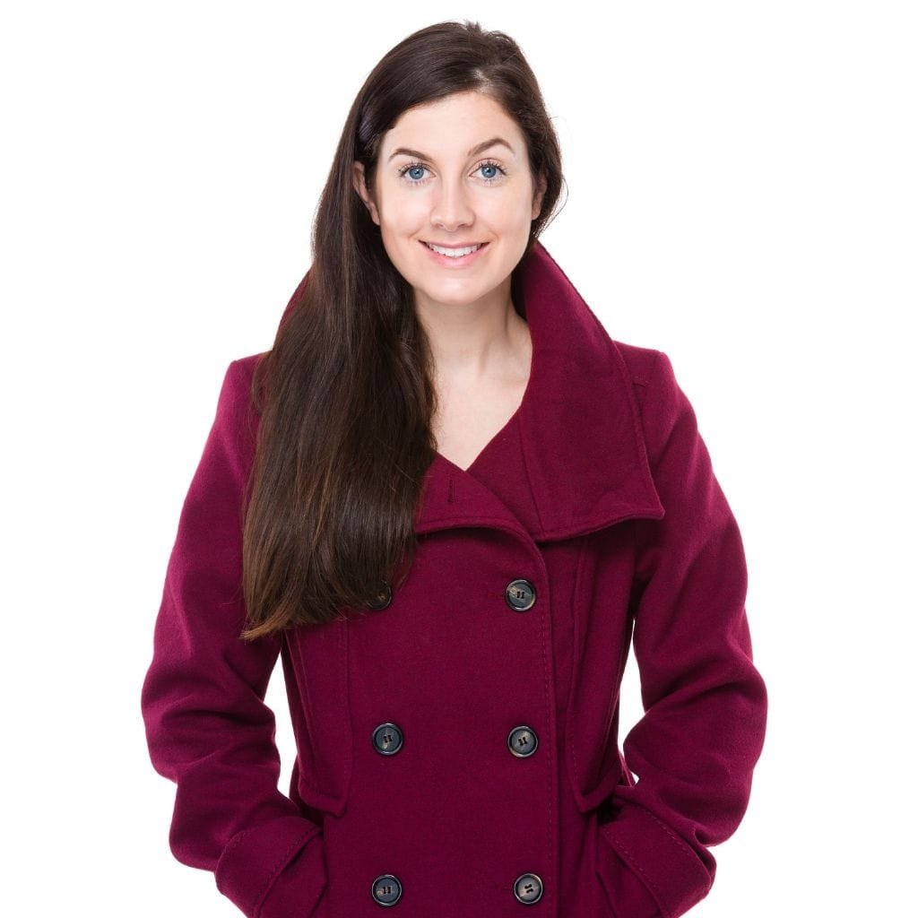 Alt text (short, accessible): A smiling woman with long dark hair wearing a burgundy double-breasted coat against a white background.

