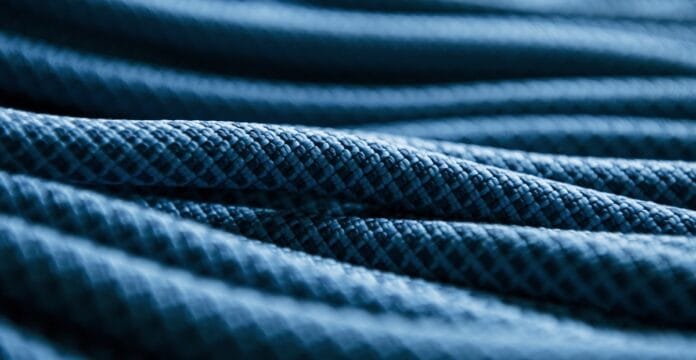 A close-up of stacked dark blue fabric with a textured, woven pattern and soft folds.