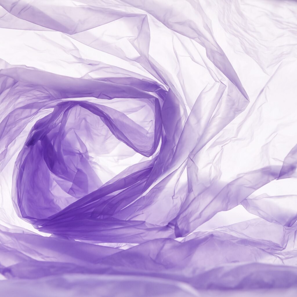 Close-up of delicate, translucent crystal organza fabric in soft lavender tones, swirling in soft folds.