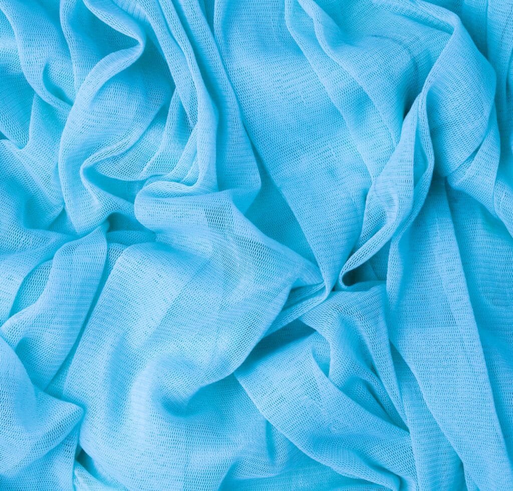 "Close-up of soft, light blue tulle linen fabric with delicate, sheer texture and airy folds."