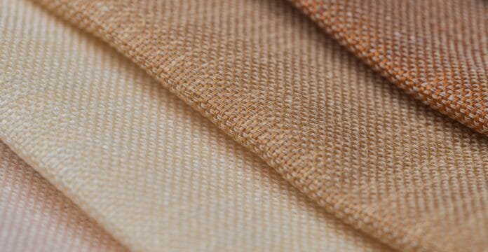 Close-up view of layered cotton fabrics in neutral beige and tan tones, showing a plain weave texture.