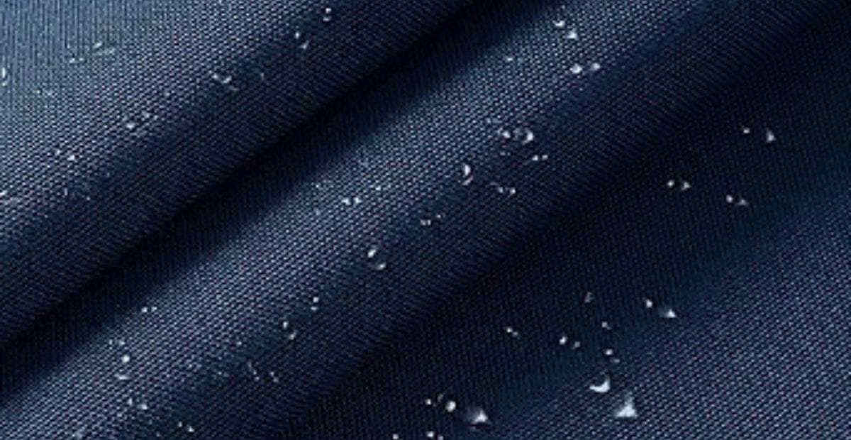 Close-up of water droplets on dark blue water-resistant fabric.