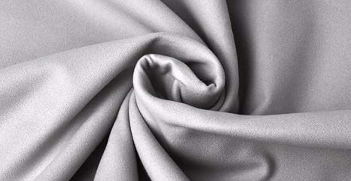 Close-up of smooth grey polyester microfiber fabric with soft folds and elegant texture.