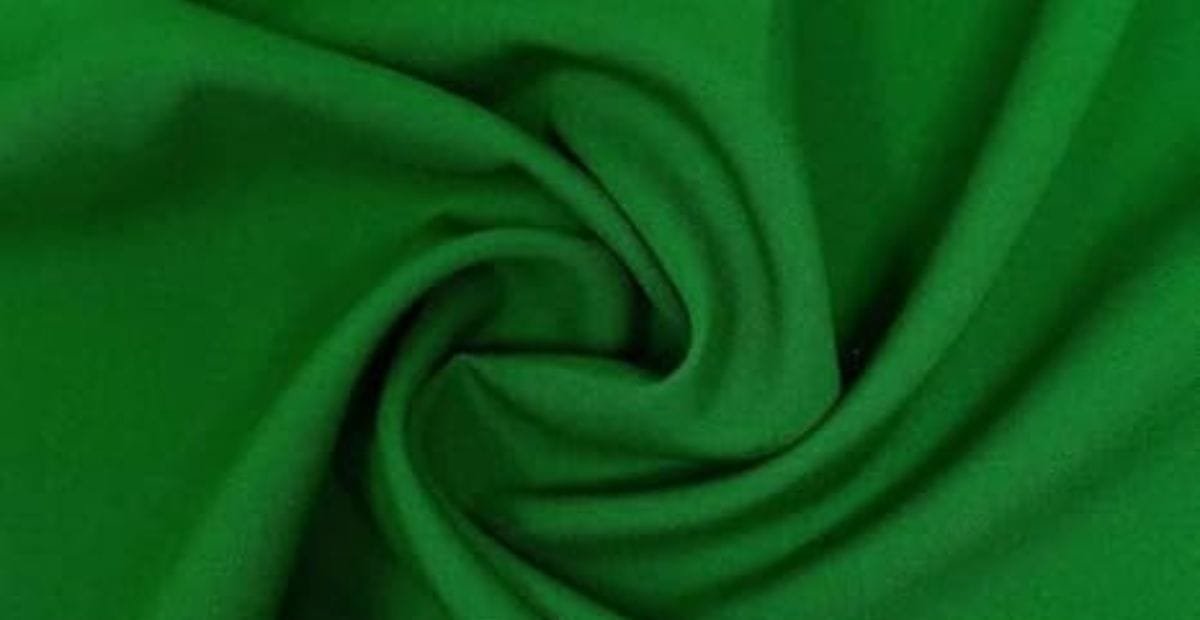Green polyester fabric folded in swirls, raising the question does polyester make you sweat during wear.