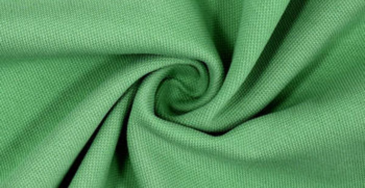 Close-up of green polyester fabric with a smooth texture, twisted into a swirl pattern.