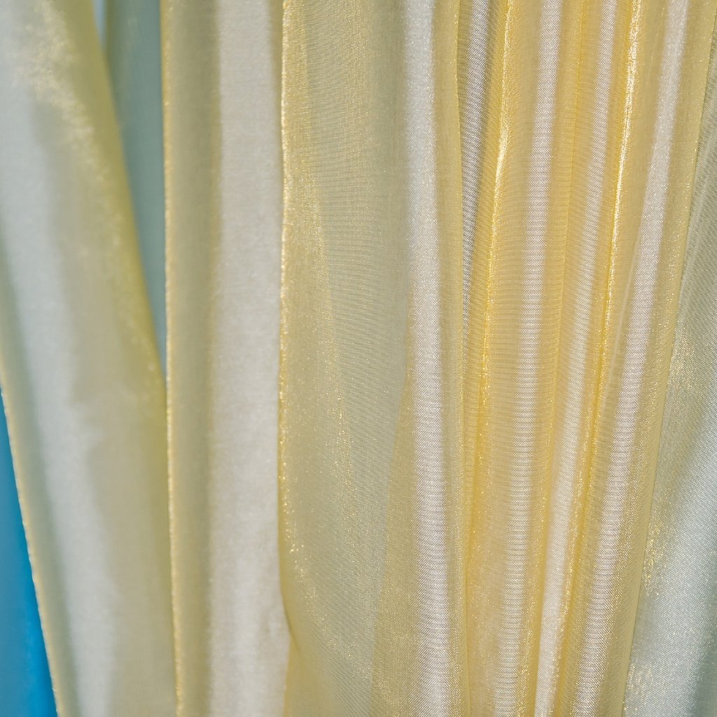 Close-up of pale-yellow shot organza fabric with a crisp, sheer texture and light diagonal sheen.

