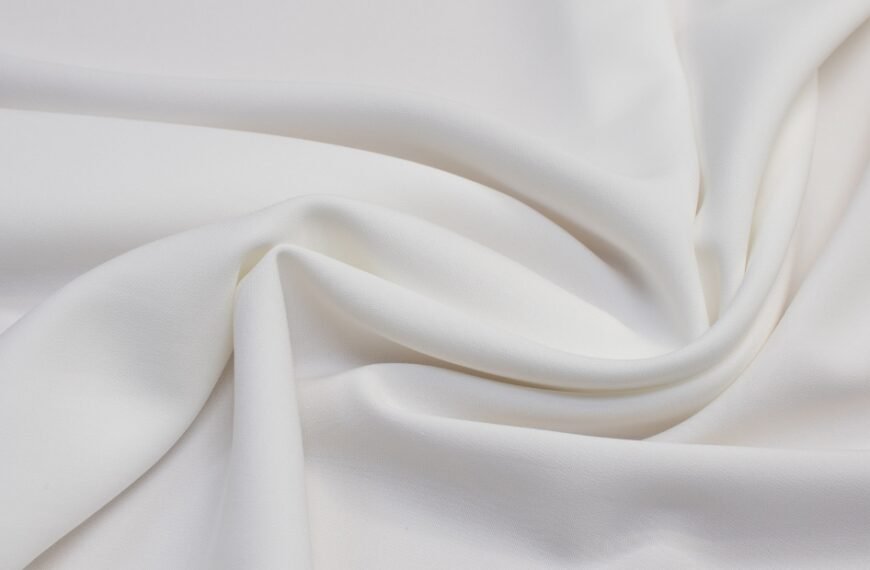 Close-up of smooth, white viscose rayon fabric draped and twisted to show its soft texture and fluid drape.