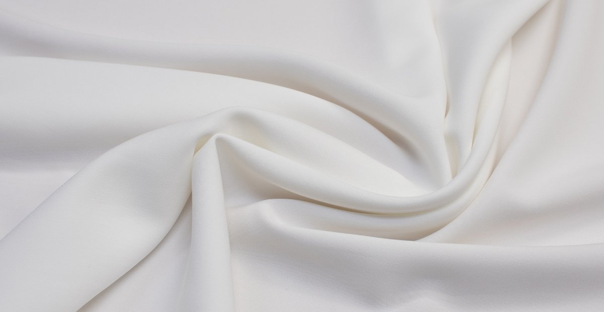 Close-up of smooth, white viscose rayon fabric draped and twisted to show its soft texture and fluid drape.