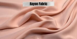 Close-up of soft, light peach rayon fabric with gentle folds, showcasing the texture.