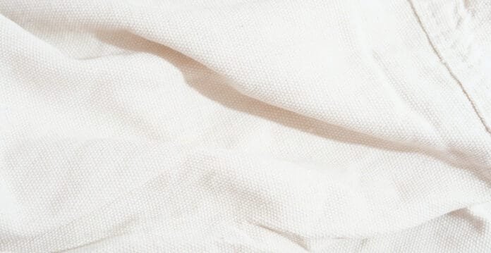 up view of light-colored linen fabric with a soft, textured weave and gentle folds.