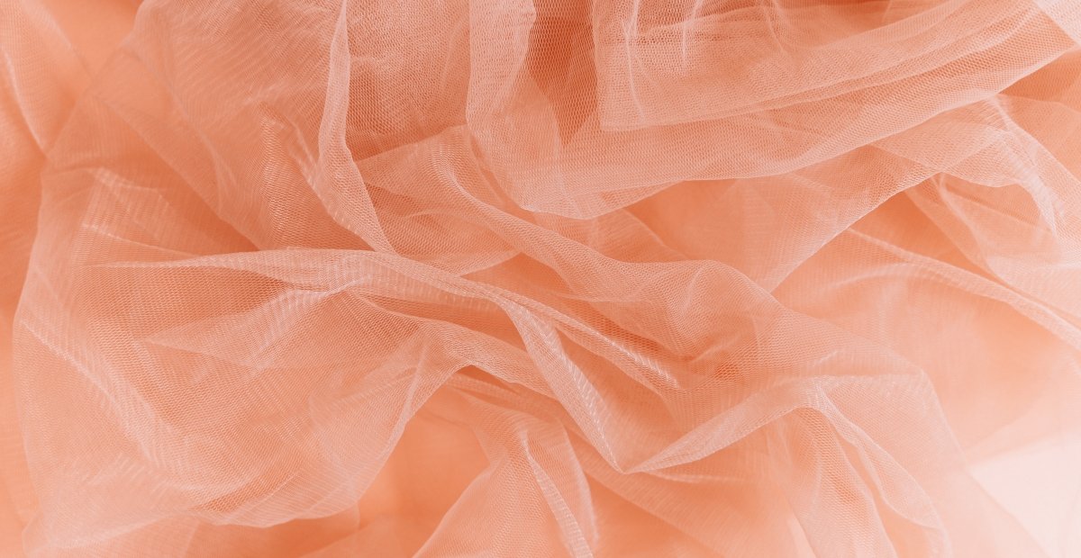 Soft peach-colored crushed organza fabric with irregular folds and sheer texture.
