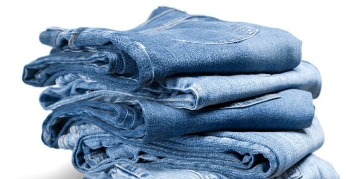 A neatly folded stack of blue jeans on a white background.