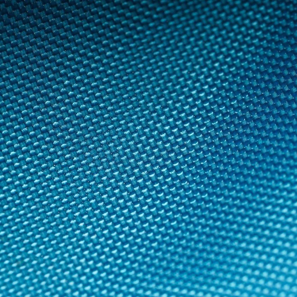 Close-up of a blue textured fabric with a small repeating pattern of raised squares. oxfard cotton fabric