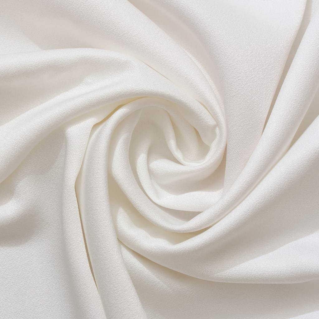 Close-up of soft white Pima cotton fabric, gracefully folded into gentle spirals to show its smooth, luxurious texture.