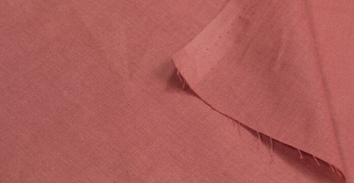 A close-up of a red fabric with a folded corner and frayed edges.
