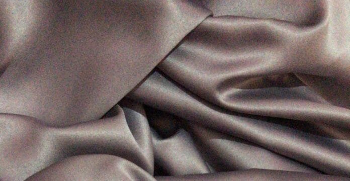 Close-up of soft, folded gray fabric with smooth shadows and highlights.