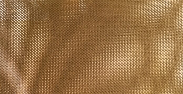 Close-up of brown polyester fabric with a repeating woven texture, showing small, uniform diamond-like patterns and subtle sheen.