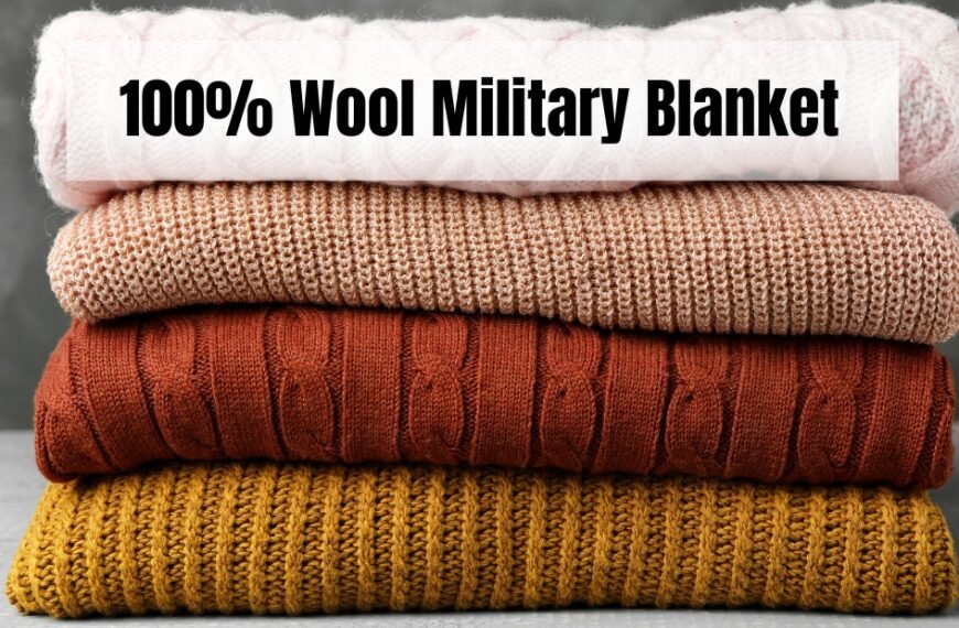 A neatly stacked pile of knitted wool blankets in four colors (pale pink, light brown, orange-brown, and mustard) resting on a gray surface with a plain dark backdrop. The top banner reads “100% Wool Military Blanket.