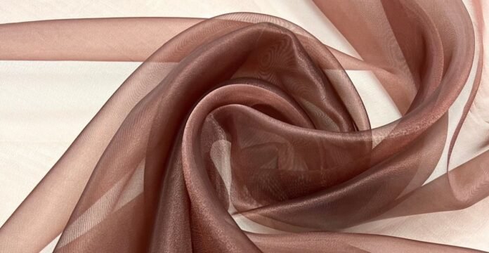 A soft, sheer brown fabric laid in swirling folds on a light background. Brown Organza Fabric