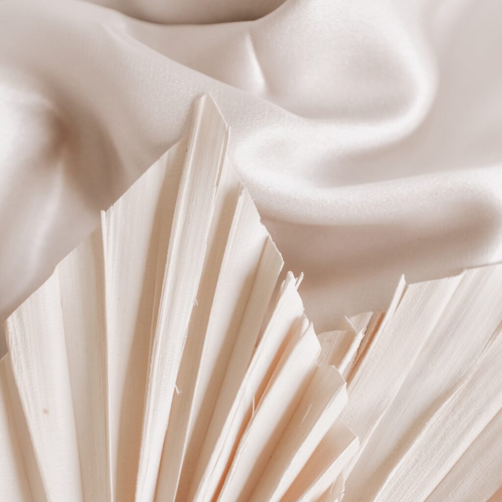 "Close-up of soft, pleated rayon silk fabric in ivory, with light folds and gentle shadows."