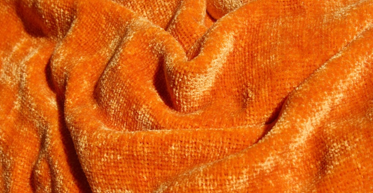 Close-up of orange textured fabric gathered in soft folds.
