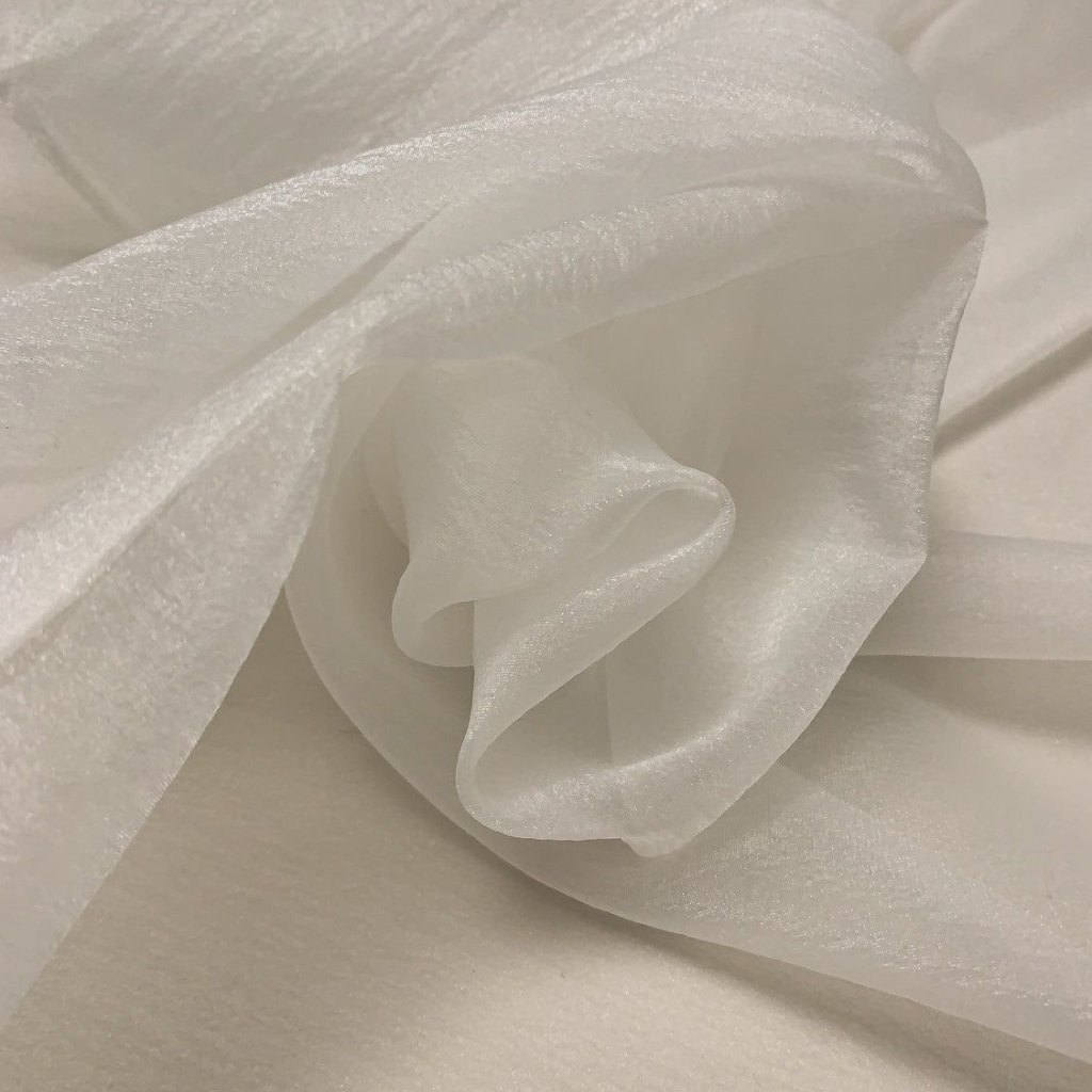 White Organza Fabric: Elegant Style for Dresses and Interiors 31 A close-up image of white, silky fabric softly draped and gathered, showing smooth folds and sheer texture.