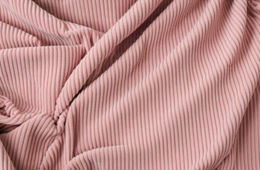 Close-up of pink pleated corduroy fabric with soft folds.