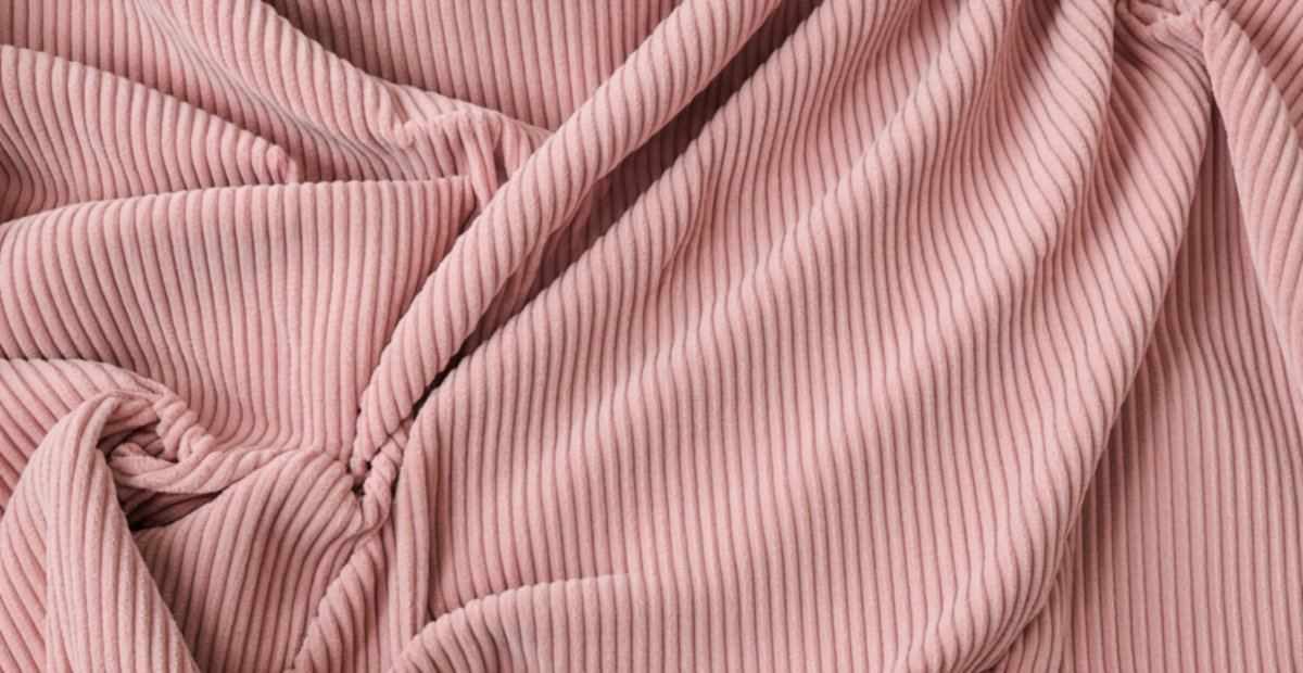 Close-up of pink pleated corduroy fabric with soft folds.