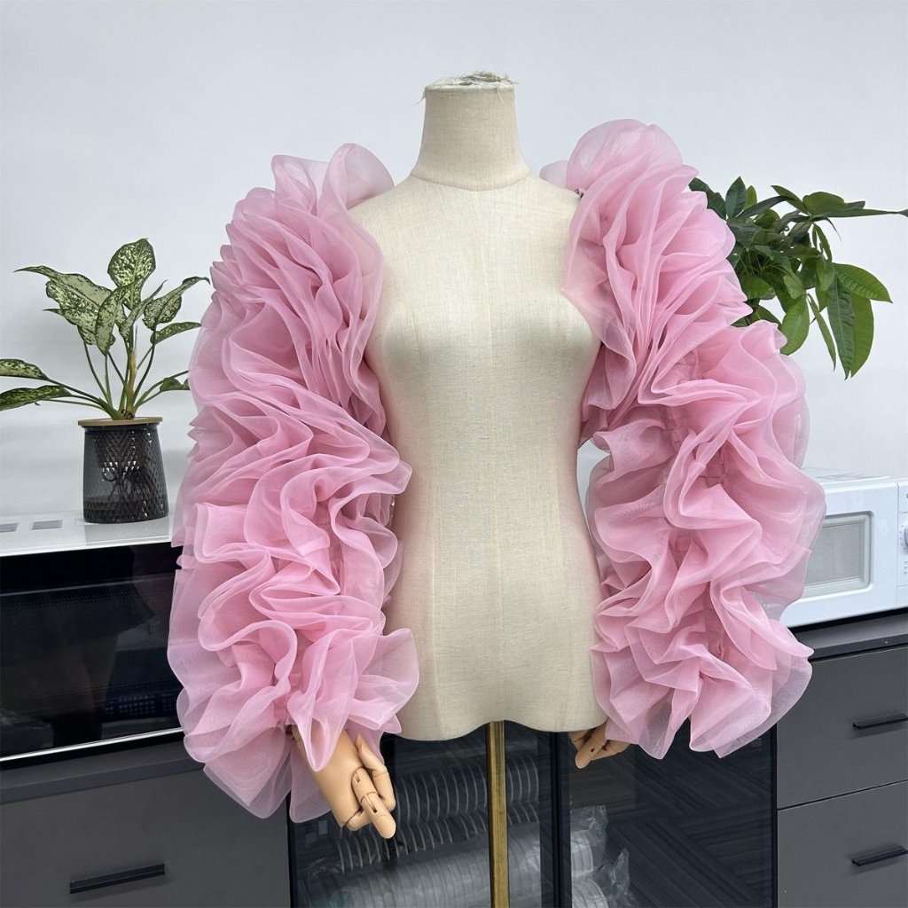Pink sheer ruched bolero with voluminous puff sleeves on a dress form.