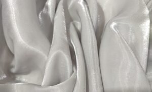 Close-up of lustrous metallic organza fabric with soft, flowing folds and a subtle sheen that reflects light. Metallic Organza Fabric